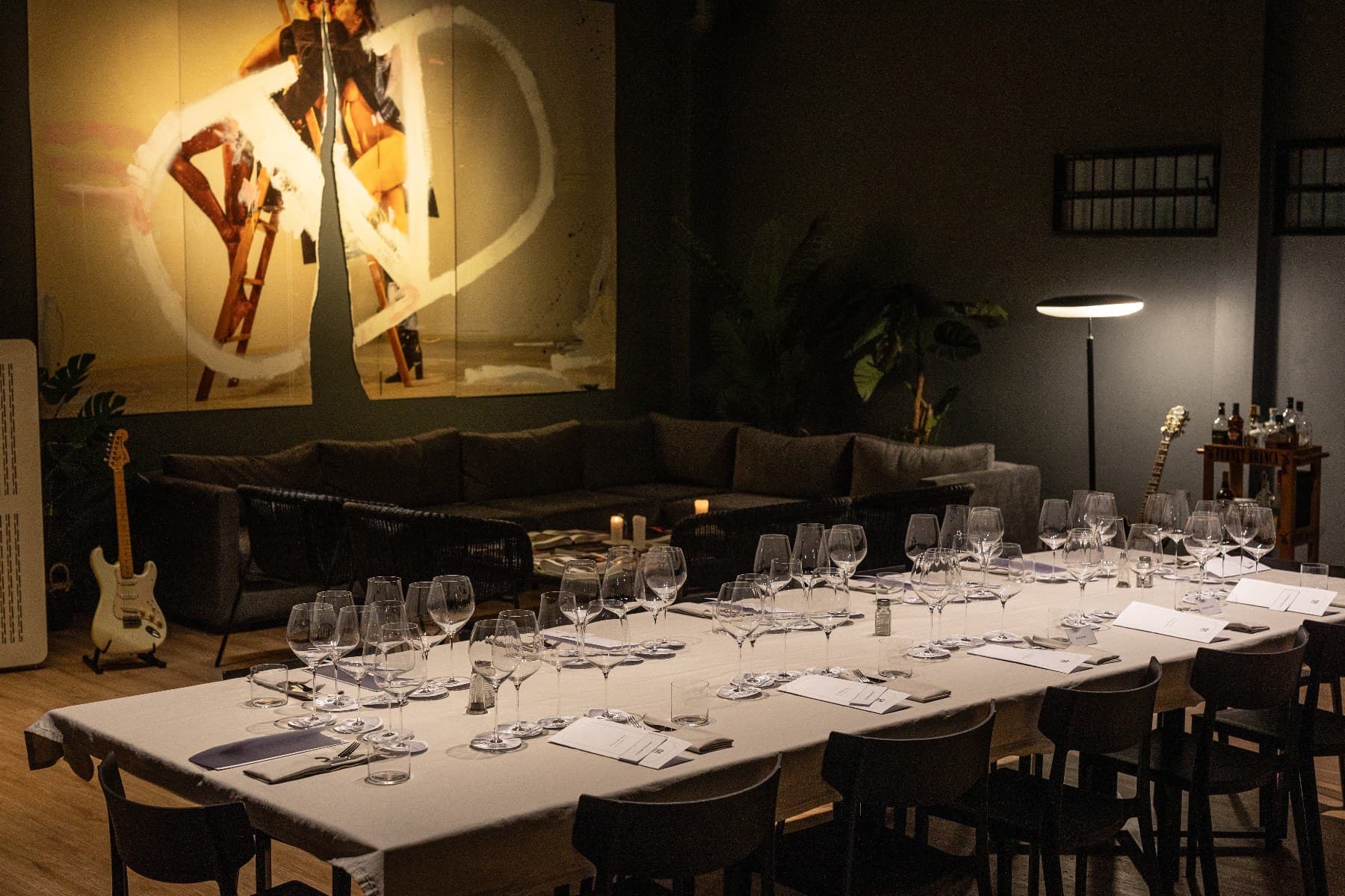 La mesa larga de Casa VG puesta para una cena, con las copas y la luz cálida del salón
